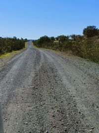 Road amidst field against clear sky