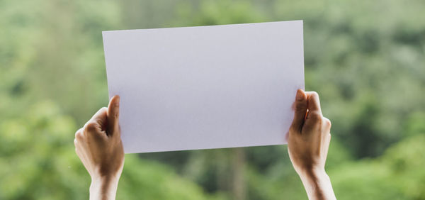 Close-up of hand holding paper against blurred background