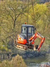 Excavator hanging on chain in forest