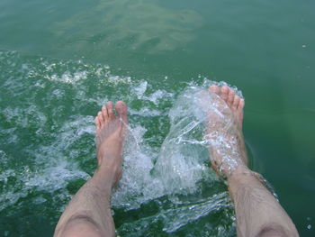 Low section of man splashing water in sea