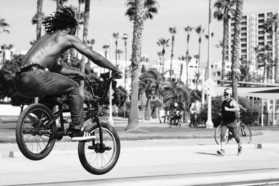 Full length of shirtless man riding bicycle on road