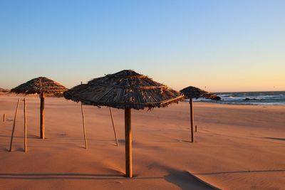 Lifeguard hut on beach against clear sky during sunset