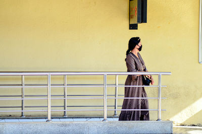 Side view of woman standing against wall