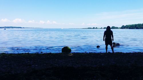 Rear view of silhouette friends on beach against sky