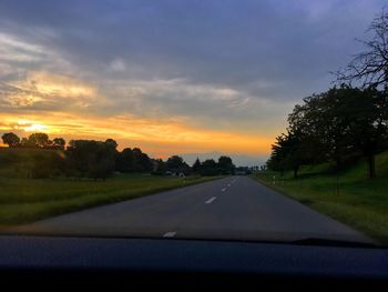 Scenic view of road against cloudy sky during sunset