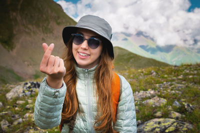 Portrait of young woman wearing sunglasses while standing against mountain