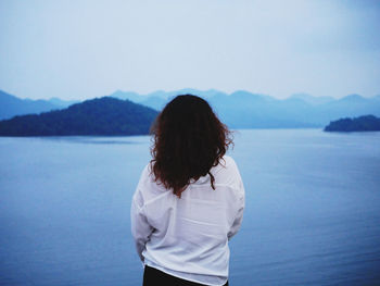 Rear view of woman looking at sea against mountain