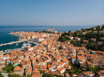 High angle view of townscape by sea against clear sky