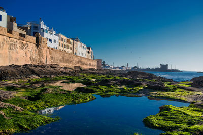 Buildings at waterfront against blue sky