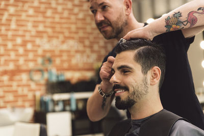 Midsection of barber cutting man hair in salon