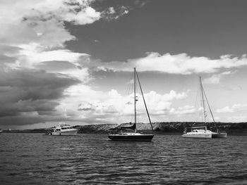 Sailboats sailing in sea against sky