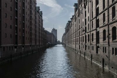 Canal amidst buildings in city against sky