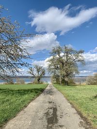 Road amidst field against sky