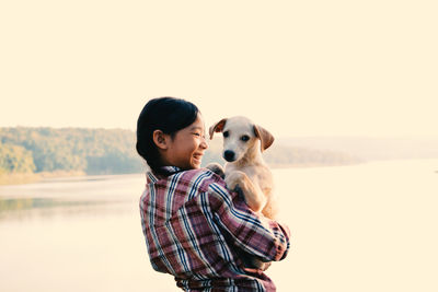 Side view of young woman carrying dog 