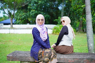 Portrait of women standing by trees against plants