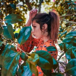 Young woman standing by plant leaves