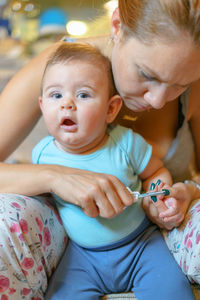 Mid adult woman with son cutting fingernail at home