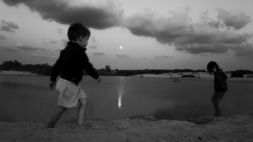 Siblings playing on beach against sky