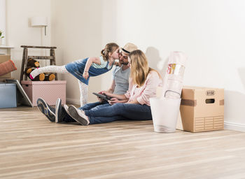 Parents and daughter using tablet in new home