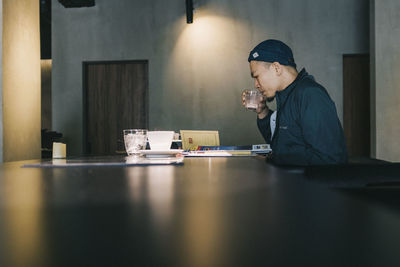 Side view of man drinking coffee at table in cafe