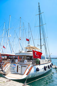 Sailboats moored in sea against clear blue sky