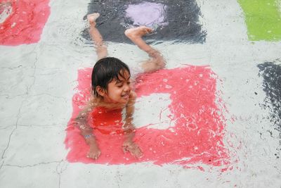 High angle view of boy with umbrella on wet floor