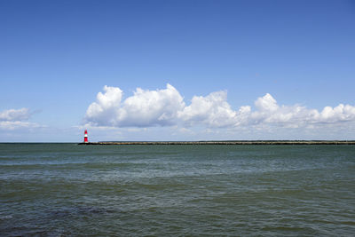 Lighthouse by sea against sky