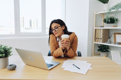 Young woman using mobile phone while sitting on table