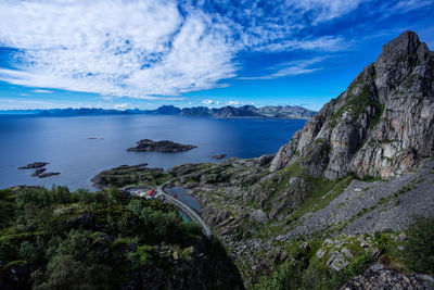 Panoramic view of road between fjord and mountains over the horizon