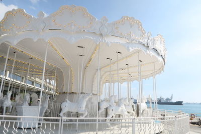 View of amusement park by sea against sky