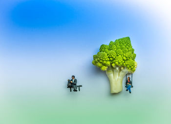 Figurine and broccoli against blue background