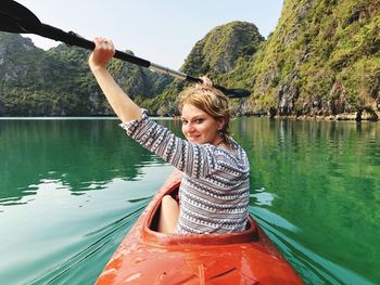 Young woman holding boat in lake against mountain