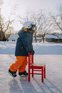 Preschool boy learning how to skate at golden hour outdoor ice rink