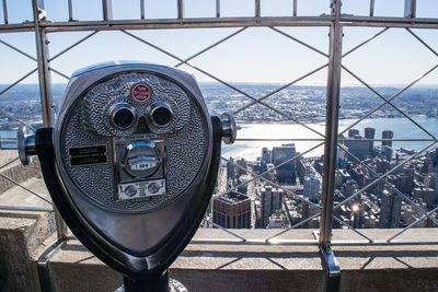 Coin-operated binoculars at observation point against cityscape