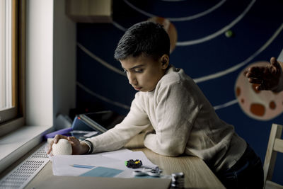 Autistic boy holding stress ball while reading book at home