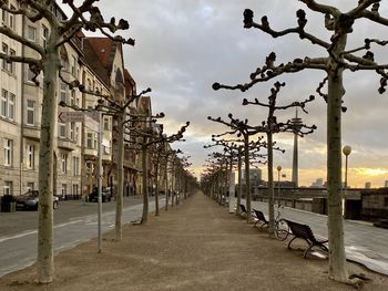 Empty footpath by buildings against sky