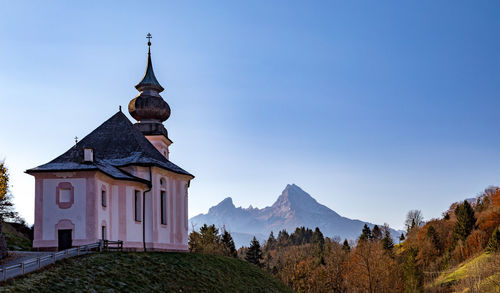 Temple against building and mountains against clear blue sky