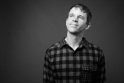 Portrait of young man standing against black background