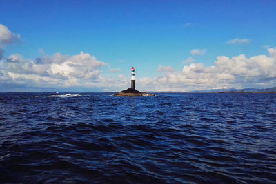 Lighthouse by sea against sky