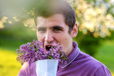 Portrait of handsome caucasian man with cone flowers in lilac garden funny attractive brunette