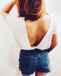 Rear view of young woman backless top against white wall