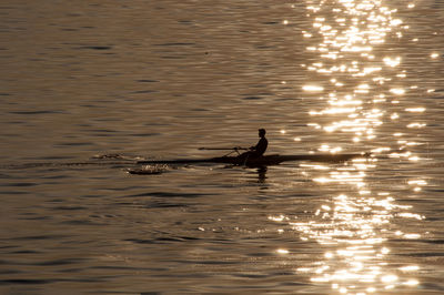 Silhouette man in sea during sunset