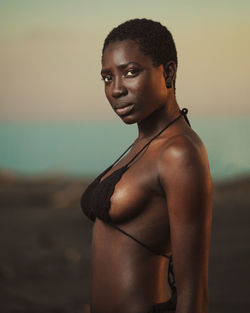 Portrait of shirtless young woman standing on beach