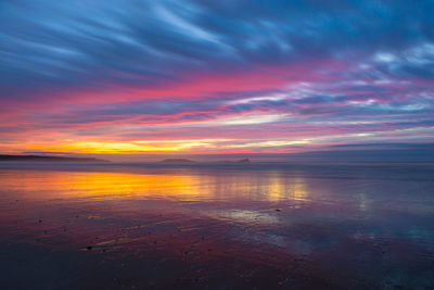 Scenic view of sea against dramatic sky during sunset