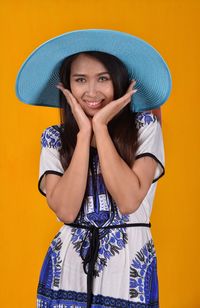 Portrait of a smiling young woman against yellow background