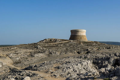 Built structure on landscape against clear blue sky