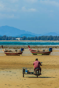 Man riding motorcycle at beach against sky