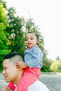 Closeup portrait of a baby boy sitting on his father's shoulders