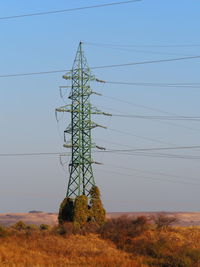 Low angle view of electricity pylon on field against sky