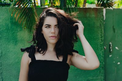 Portrait of beautiful young woman standing against wall